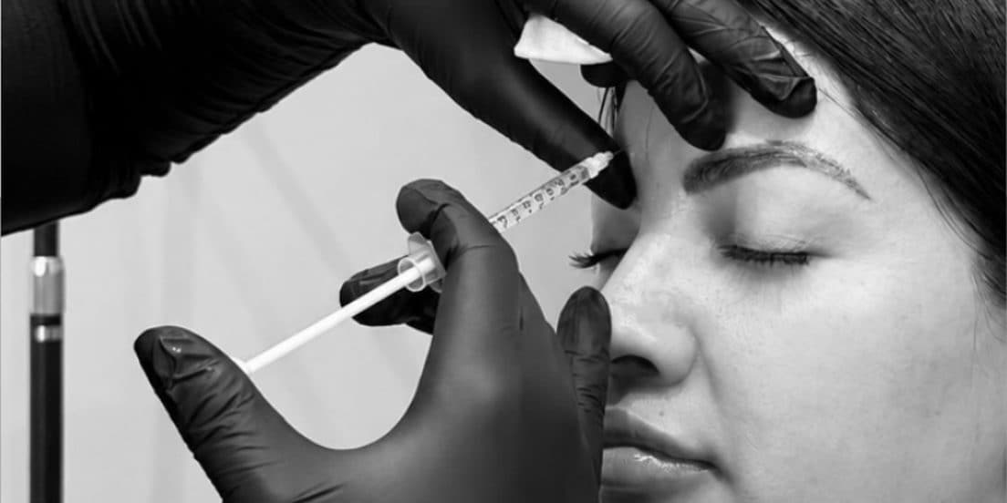 A provider injecting a client’s brow with gloved hands